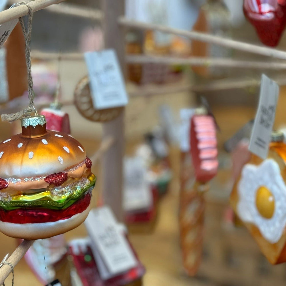 Hamburger-shaped ornament hanging among other decorative items with blurred background